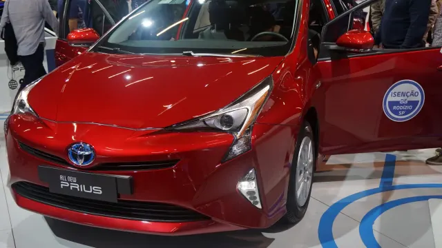 Diferença entre carro elétrico e híbrido: Toyota Prius vermelho em exposição no Salão de São Paulo, um híbrido útil para…